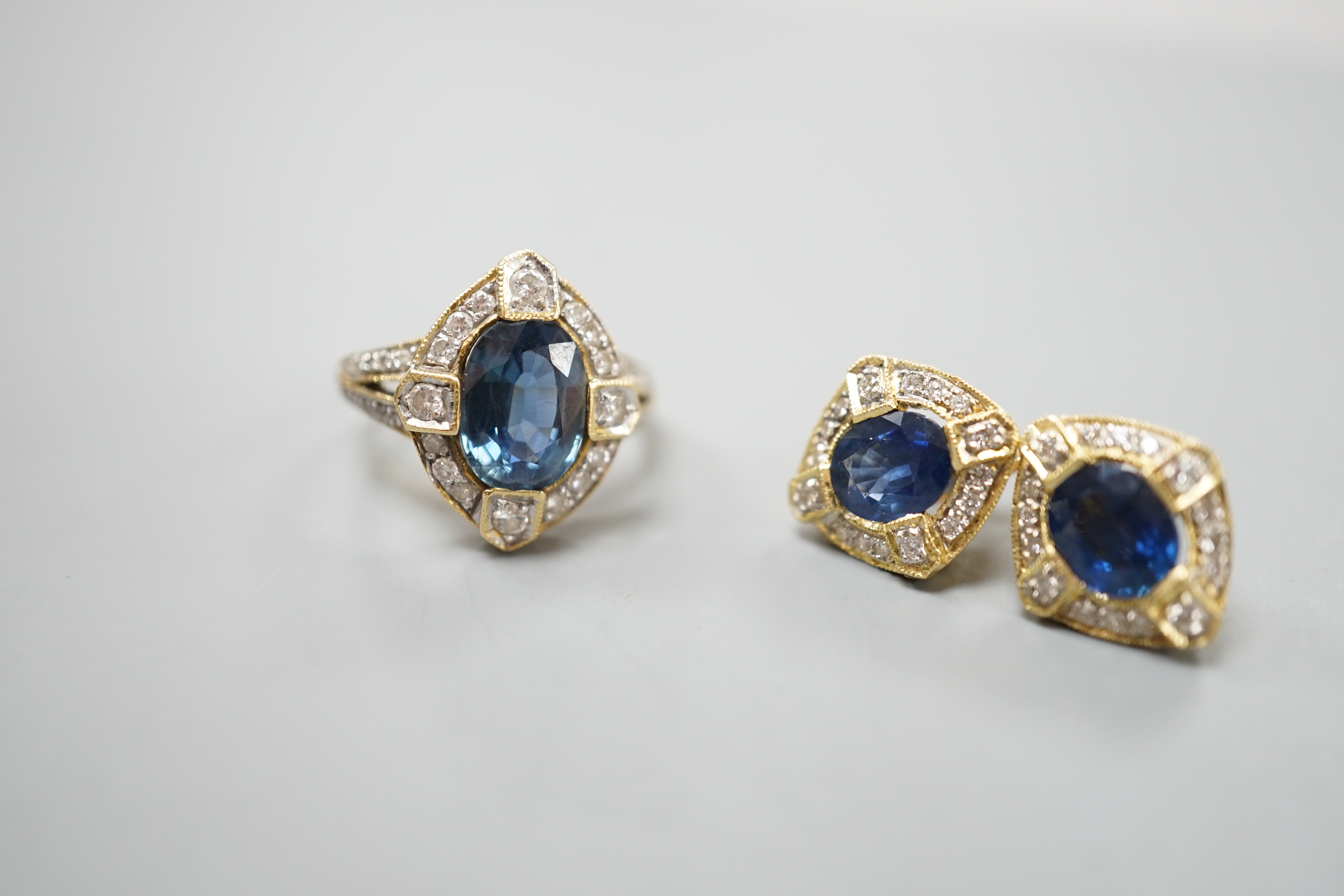 A modern suite of 18k, sapphire and diamond cluster set jewellery, comprising a dress ring, size L/M and pair of earrings, 14mm, gross weight 9.9 grams.